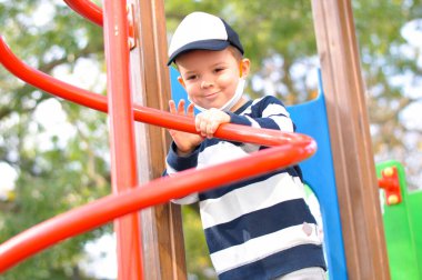 Dört yaşında sevimli bir anaokulu öğrencisi oyun alanında eğleniyor..