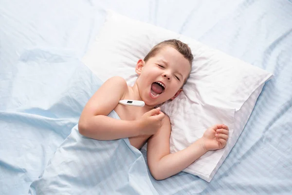 病気の子供がベッドに横になって泣き気温を測定して — ストック写真