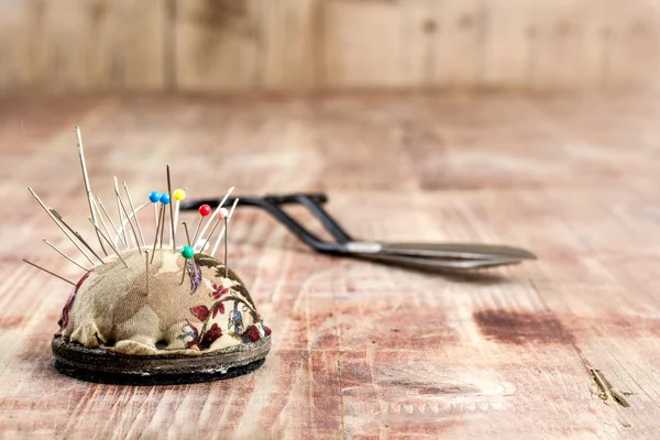 Old scissors and pincushion on a wooden background — Stock Photo, Image