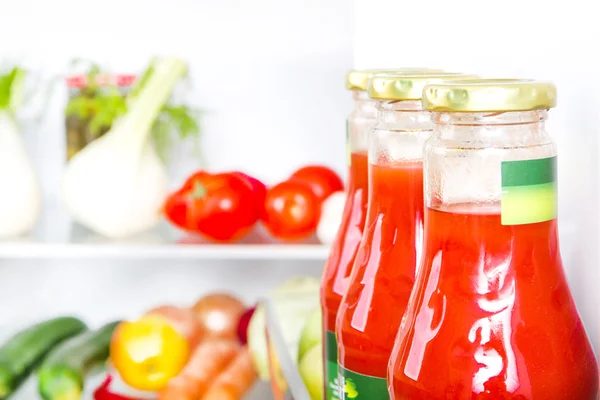 Bottle of tomato juice with fruits and vegetables at background