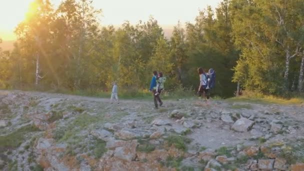 Junge Eltern mit drei Kindern wandern bei Sonnenuntergang auf einem Bergweg. — Stockvideo