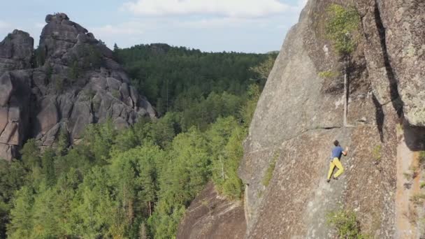 Letecký pohled na statečného mladého muže, jak leze po skalní stěně bez pojištění. — Stock video