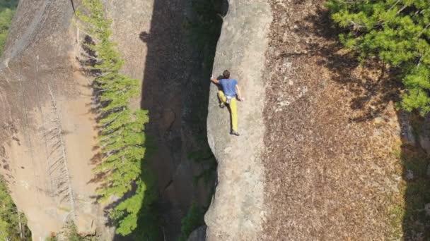 Un disparo aéreo de un joven escalando cuidadosamente una pared de roca sin una red de seguridad. — Vídeo de stock