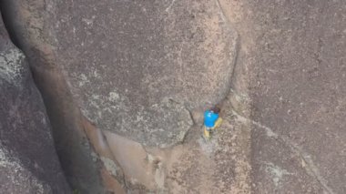 Genç ve cesur bir adamın kaya yarığında tek başına tırmanışının en üst görüntüsü..