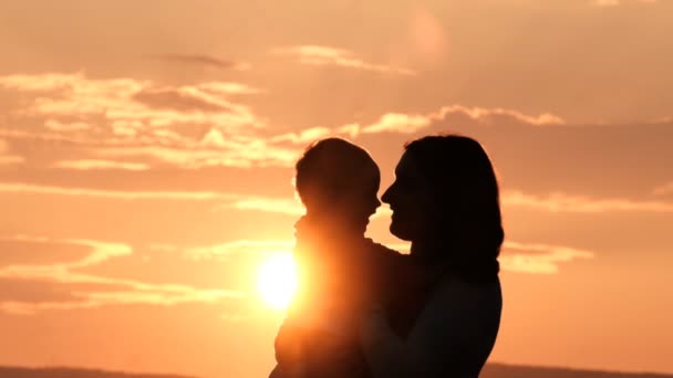 Silhouette egy anya megcsókolja a fiát naplementekor. — Stock videók