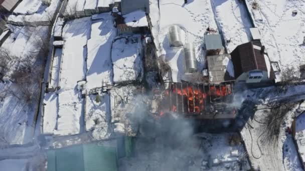 Vista superior de una casa en llamas en un pueblo en invierno. — Vídeo de stock