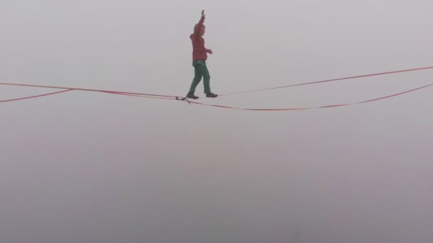 Detailní záběr mladého muže, jak kráčí na těsném praku v mlze. Slackline s pojištěním. — Stock video