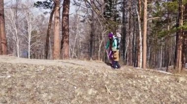 Genç ve aktif annenin baharda dağlarda yürüyüş yapan iki oğluyla görüntüsü.