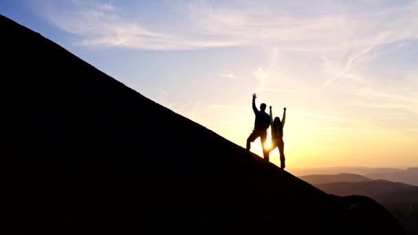 Um jovem casal alegremente levanta as mãos na montanha. — Vídeo de Stock