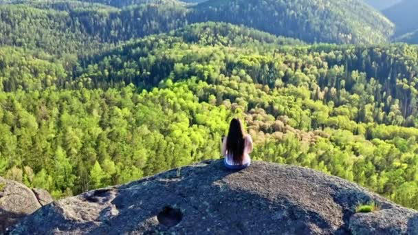 岩だらけの崖の端に座っているラップトップで働いている若い女性のトップビュー. — ストック動画