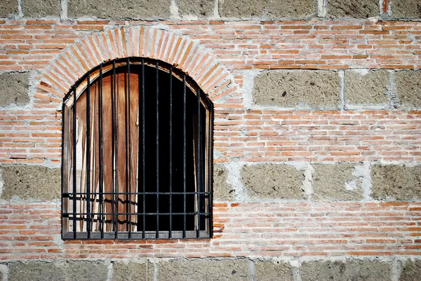 Vieja ventana con barras en una pared de ladrillo y piedra —  Fotos de Stock