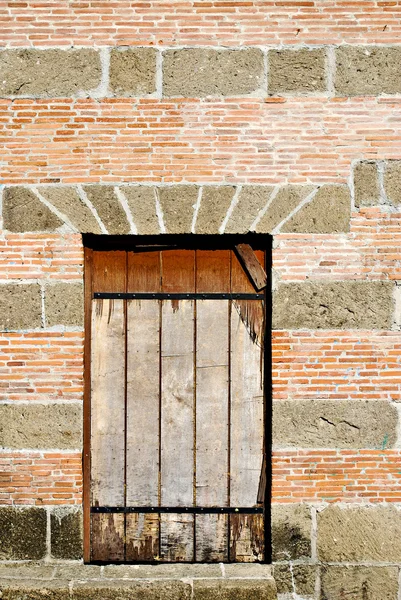 Vieja ventana con barras en una pared de ladrillo y piedra —  Fotos de Stock