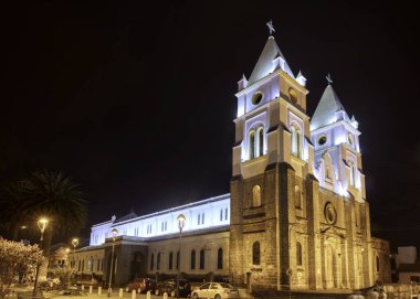 Guaranda, Bolivar province, Ecuador/ November 2013: View of the Guaranda Cathedral and central plaza, at night time. clipart