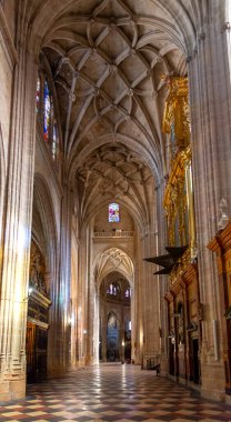 The Segovia Cathedral interior showcases towering Gothic arches and an ornate vaulted ceiling. Massive columns frame the central altarpiece and detailed stained glass