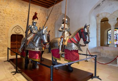 Segovia 'nın Alczar' ının içindeki ortaçağ zırhları ışığı yansıtıyor. Çelik göğüs zırhları ve miğferler duvara monte edilmiş kraliyet kalkanının yanında dururlar.
