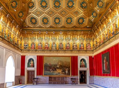 Tarihi Alczar şatosundaki bir kraliyet salonunda süslü bir altın Mudjar tavanı bulunur. Zengin kırmızı kadife duvarları örtüyor Oturmuş tarihsel figürlerin frizinin altında