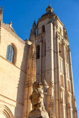 Segovia Katedrali 'nin çan kulesinin ve yan cephesinin dramatik, günbatımına yakın, günbatımına yakın Gotik taş işçiliği ve düşük koruma duvarı sergileniyor.