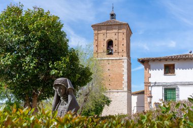 İspanya 'nın Chinchn kentindeki ortaçağ tuğla saat kulesi (Torre del Reloj), genç ağaçlar ve orjinal taş duvar parçalarıyla çevrili bir halk meydanında ayakta duruyor.