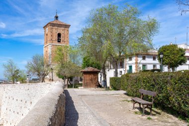 İspanya 'nın Chinchn kentindeki ortaçağ tuğla saat kulesi (Torre del Reloj), genç ağaçlar ve orjinal taş duvar parçalarıyla çevrili bir halk meydanında ayakta duruyor.