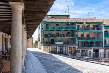Chinchn 'in Plaza Belediye Başkanı' nın turkuaz ahşap balkonları ve ön planda ağır taş sütunları olan üç katlı kendine özgü binaları ön plana çıkaran manzarası..