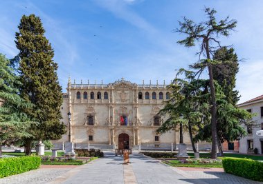 Alcal de Henares, İspanya - 9 Nisan 2025: Alcal Üniversitesi 'nin ana girişinin taş cephesi, güzel dekore edilmiş pencereleri ve belirgin bir girişi ile tarihi bir ön plazaya bakıyor.