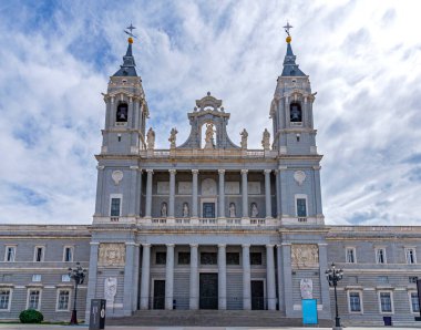 Madrid 'deki Almudena Katedrali, iki çan kulesi, merkezi bir kubbe ve dramatik mavi ve beyaz gökyüzünün altında büyük bir taş merdiven ile neo-Romanesk dış görünüşünü sergiliyor..