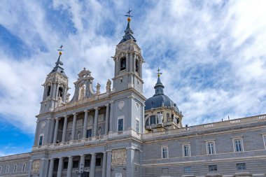 Madrid 'deki Almudena Katedrali, iki çan kulesi, merkezi bir kubbe ve dramatik mavi ve beyaz gökyüzünün altında büyük bir taş merdiven ile neo-Romanesk dış görünüşünü sergiliyor..