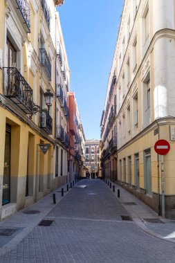 A typical street in central Madrid, lined with elegant historic buildings, balconies, and warm facades, capturing the citys lively charm and timeless architecture
