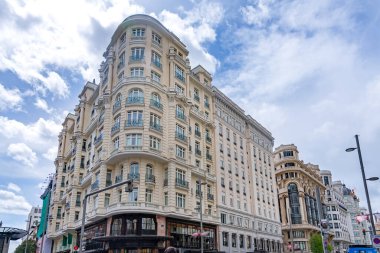 A decorative historic building in Madrid rises with curved lines, balconies, and detailed architectural features, creating a classic urban scene suited to many views
