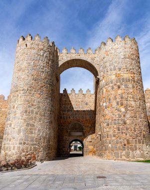 Geniş bir kemerli girişte iki geniş ortaçağ taş kulesi bulunan vila duvarlarının çarpıcı manzarası. Güçlendirilmiş kuleler, berrak mavi gökyüzünün altında gökdelenlerle yükseliyor.