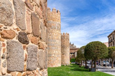 Villanın duvarlarına yakından bakınca, ortaçağ yapısının yanında manikürlü ağaçlardan ve modern araçlardan oluşan büyük yuvarlak bir taş kule ve bitişik bir duvar görülüyor.