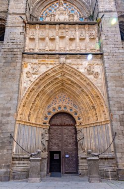 Villa Katedralleri 'nin çarpıcı bir yakın çekimi Gotik yan portalı, uzun sivri uçlu arşiv kemeriyle devasa ahşap kapılar ve zengin heykel detaylarıyla