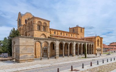 Geniş bir Roma kilisesi olan vila 'daki Baslica de San Vicente, yuvarlak kemerli ve bulutlu bir gökyüzünün altında sıcak altından yapılmış uzun arkalı bir kapı gösteriyor..