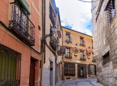 Toledo 'da dar taştan sokaklar demir balkonlu yüksek binalar, tahta pencere panjurları ve fenerler arasında esiyor, zamansız, eski şehir atmosferi yaratıyor.