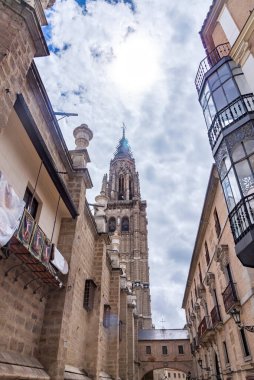 Dar tarihi binalarla çevrili Toledo Katedrali 'nin alçak açılı manzarası. Tuğla kemerli, küçük pencereli ve caddenin üzerinde asılı antik bir fener var.