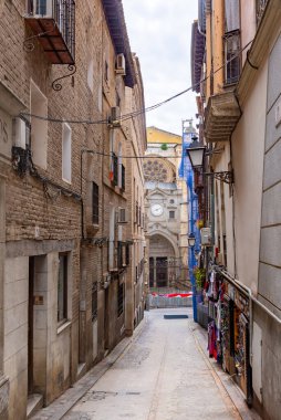 Dar bir kaldırım taşı Toledo caddesinin aşağı dikey görüntüsü, sıcak sıva cepheleri, dövmeli demir balkonlar, açıkta taş ve uzak bir ahşap balkon ile kaplı