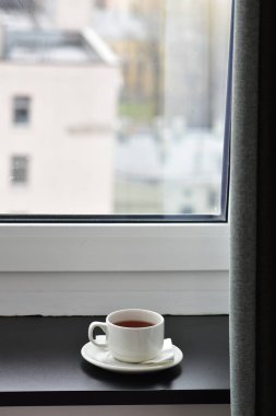 Pencerenin karşısındaki pencere eşiğinde bir fincan çay.