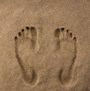 Islak kumda ayak izleri. Sahildeki adam.