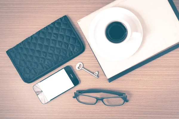 coffee and phone with stack of book,key,eyeglasses and wallet vi