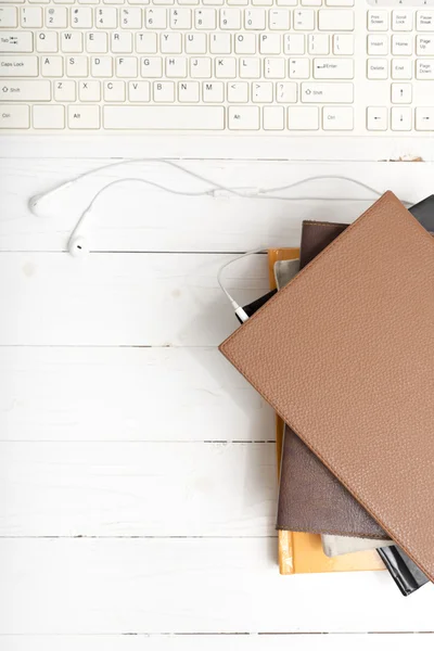 Draufsicht auf Kopfhörer mit Computertastatur mit Bücherstapel — Stockfoto