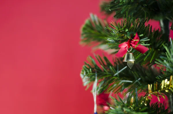 Pequeno sino na árvore de natal no fundo vermelho — Fotografia de Stock