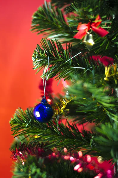 Boule de Noël bleue sur l'arbre sur fond rouge — Photo