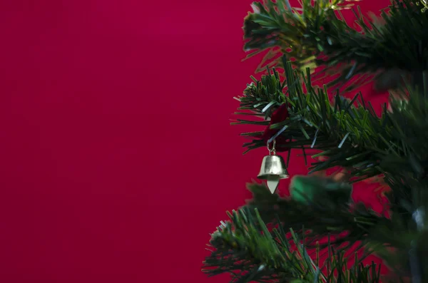 Liten klocka på julgran på röd bakgrund — Stockfoto