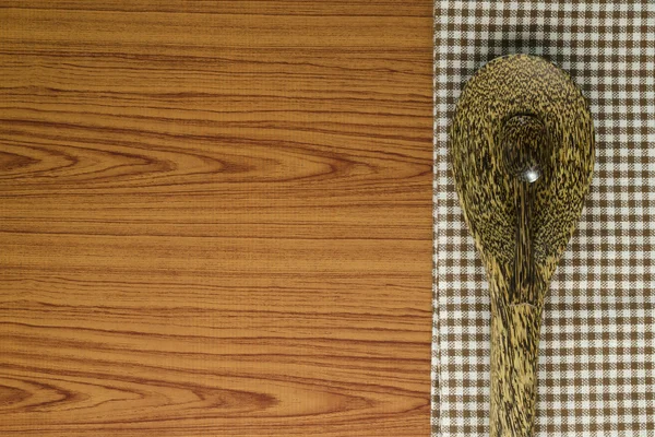 Kitchen towel with spoon on wood background — Stock Photo, Image