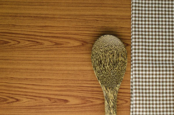 Kitchen towel with spoon on wood background — Stock Photo, Image