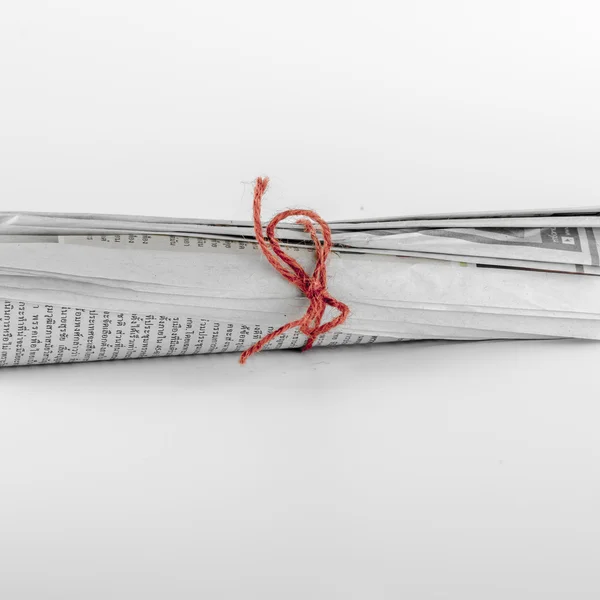 Свернутые газеты сосредоточены на красной веревке — стоковое фото