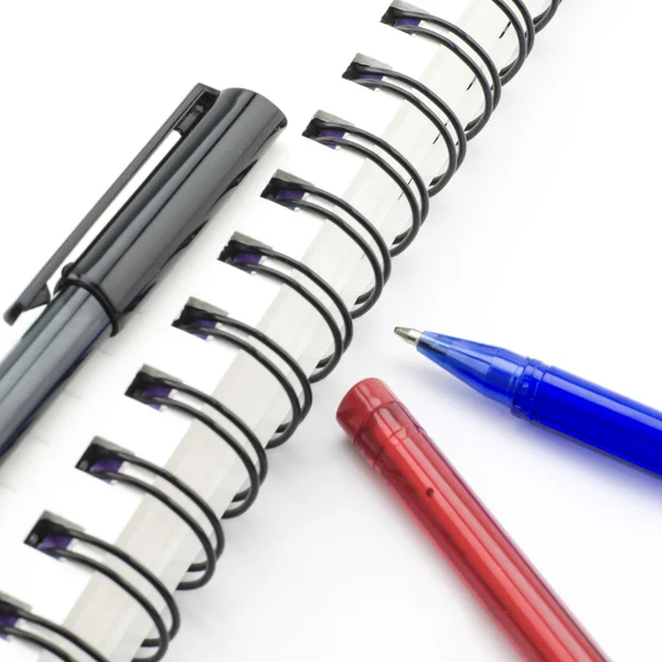 Caneta preta vermelha e azul com notebook isolado em branco — Fotografia de Stock