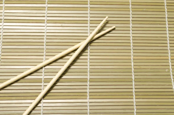 Chopsticks over bamboo mat — Stock Photo, Image