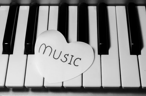 Corazón de papel en el teclado de piano blanco y negro — Foto de Stock