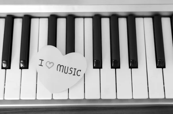 Corazón de papel en el teclado de piano blanco y negro — Foto de Stock